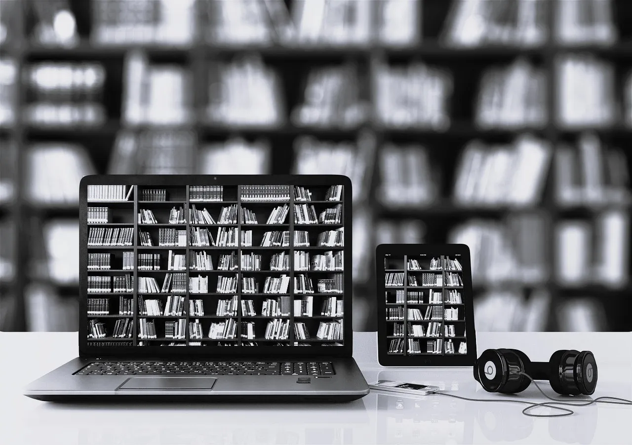 Laptop und Tablet zeigen ein Bücherregal, im Hintergrund eine Bibliothek